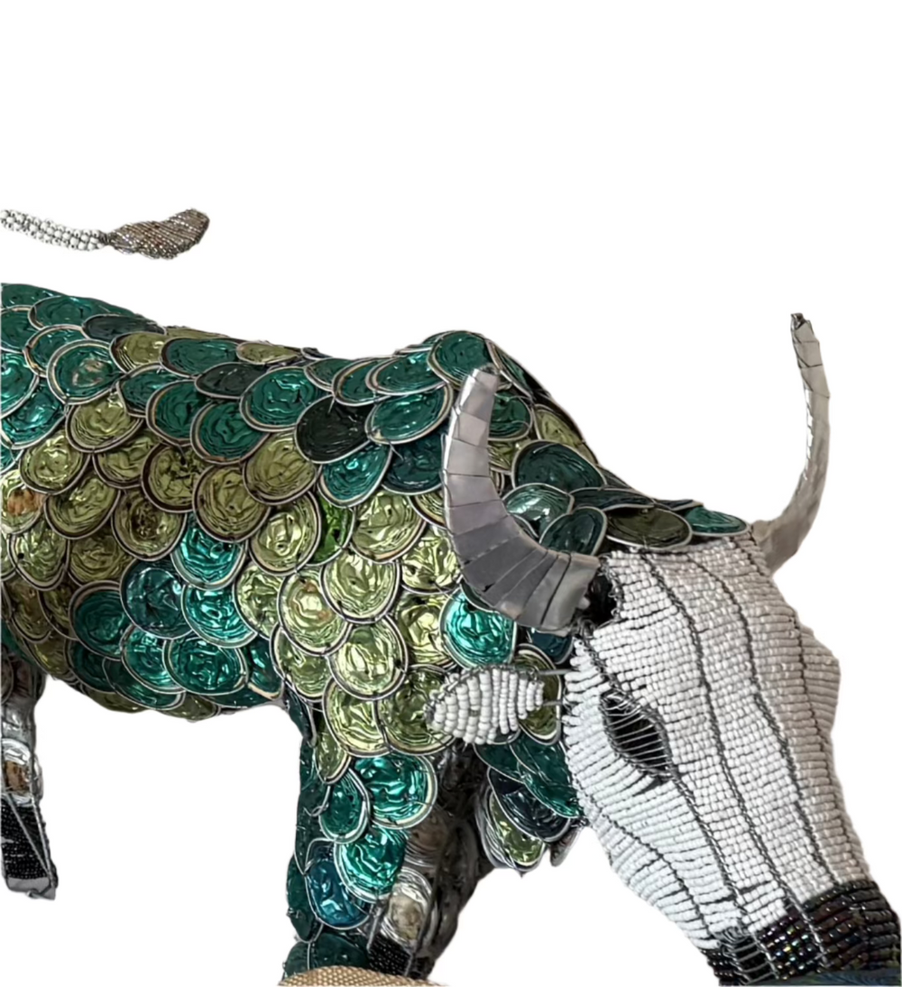 This image features a unique piece of art, a sculpture of a buffalo crafted from coffee pods. The artist has meticulously used green and blue coffee pods to create the body and pattern detailing on the buffalo, while the head and horns are made from metal, adding a contrasting element.