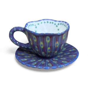 Colorful ceramic teacup and saucer with geometric pattern on a white background